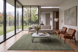 Alfombra Bindu Sage de lana en living con sofá gris y mesa de centro blanca