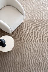 Alfombra Sahara Terra de lana junto a sillón blanco y mesa lateral