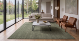 Alfombra Bindu de lana verde salvia en living con ventanales al jardín y sillones de cuero