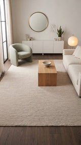 Alfombra Nest Natural de lana en living con sillón verde y mesa de centro de madera
