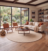 Alfombra redonda Plain Rug Miel de cáñamo en living luminoso con sillones de madera