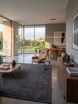 Alfombra Varua Dark Grey de Tencel en living con ventanales y sillón de cuero