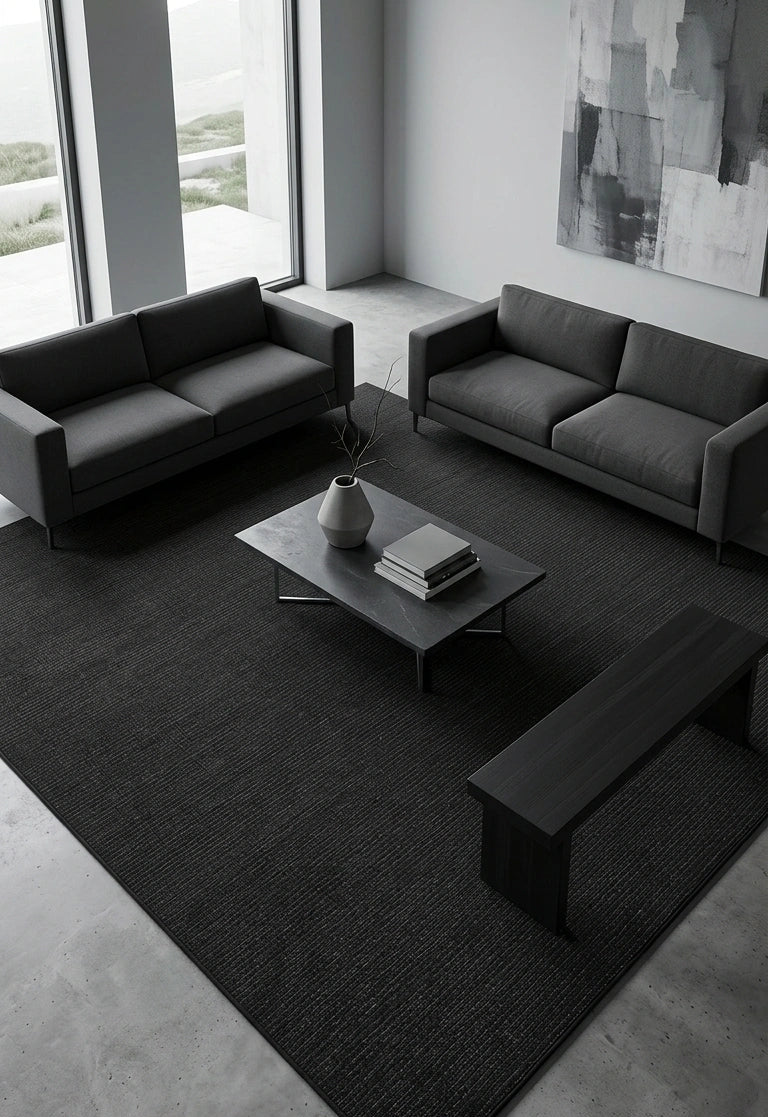 Alfombra Basai Charcoal de polipropileno negra en living con sofás negros