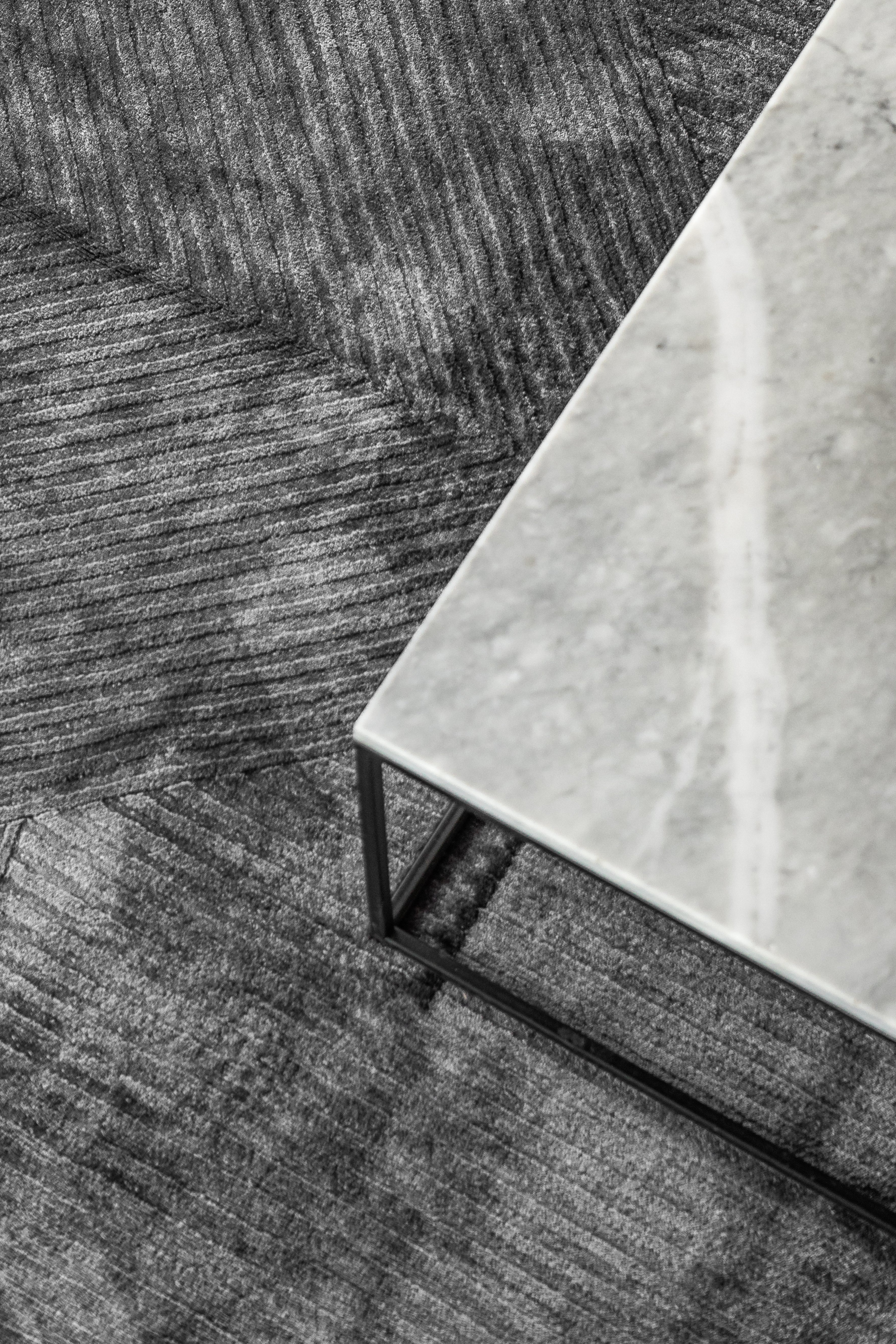 Detalle del tejido de la alfombra Komara Dark Grey de Tencel bajo mesa de centro de mármol