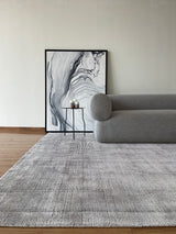 Alfombra Basanti Silver Black de Tencel junto a sofá gris curvo