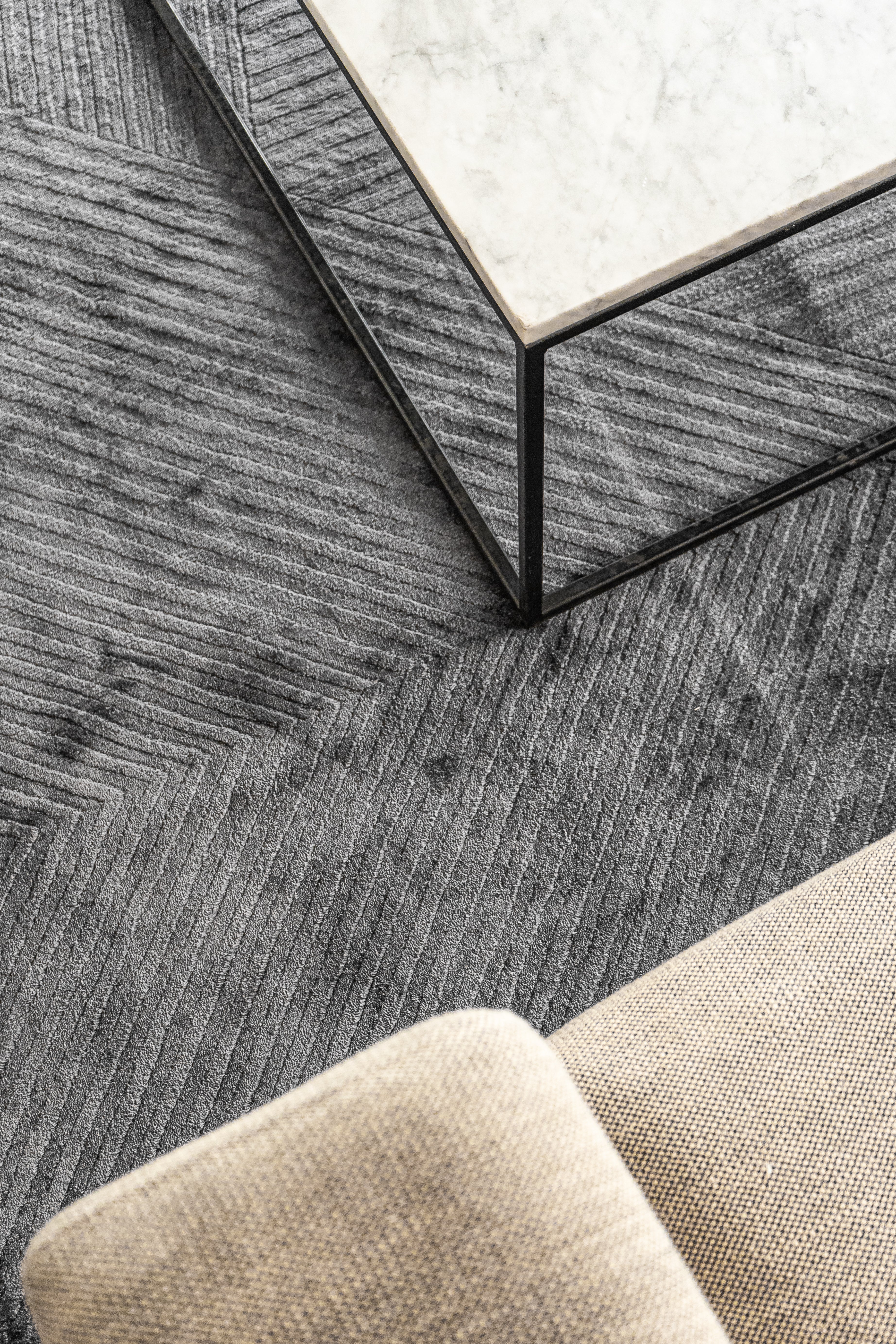 Detalle del tejido de la alfombra Komara Dark Grey de Tencel bajo mesa de centro de mármol