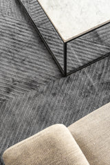 Detalle del tejido de la alfombra Komara Dark Grey de Tencel bajo mesa de centro de mármol