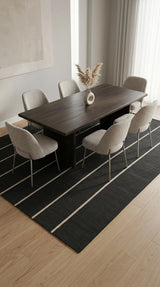 Alfombra Petra Charcoal Sand de polipropileno bajo mesa de comedor oscura