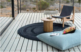 Alfombra redonda Black Chain de cáñamo en terraza de madera con mesa de centro