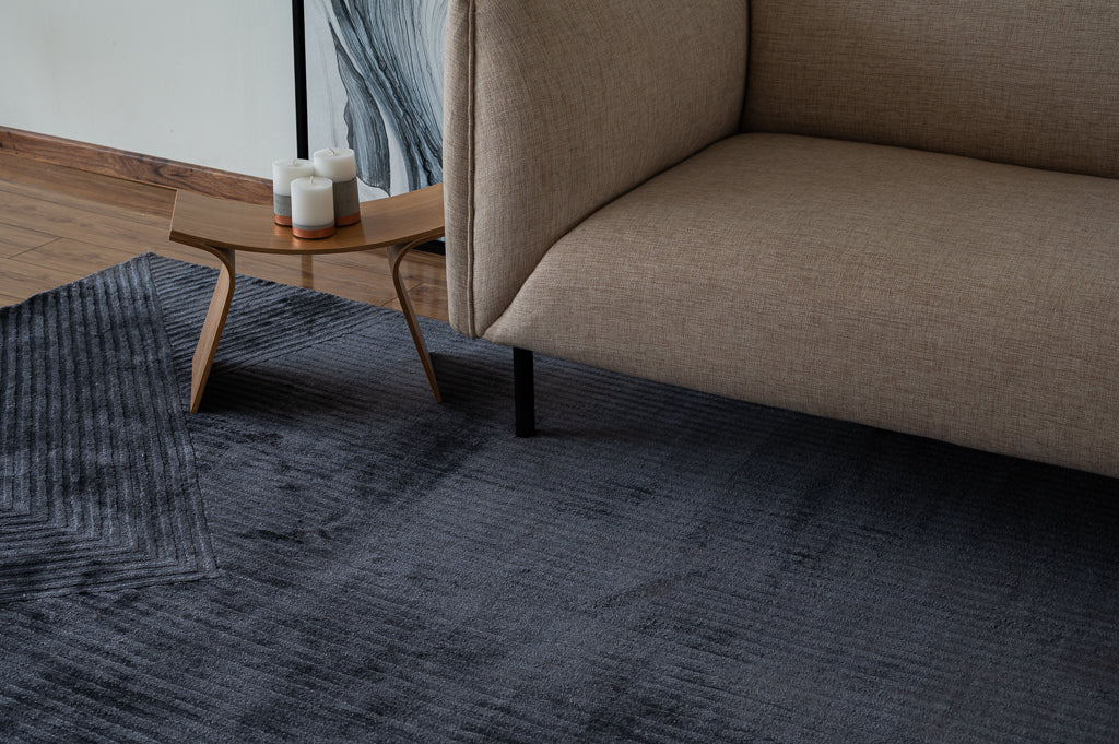 Alfombra Komara Dark Grey de Tencel junto a sillón beige